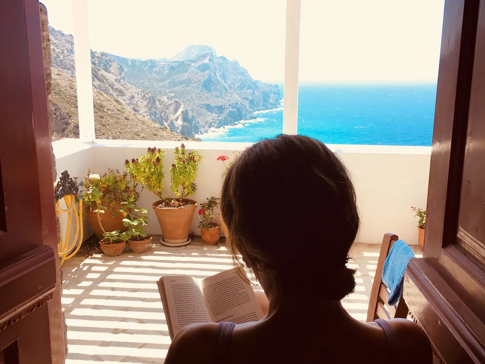 Žena na terasi apartmana iznad mora, sa otvorenim stranicama u krilu
